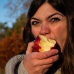 woman in gray sweater holding sliced of apple