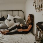 woman leaning on wall while sitting on bed