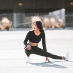 woman in black tank top and black leggings holding black and white nike shoes