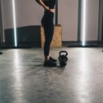 woman in black tank top and black leggings standing on white floor