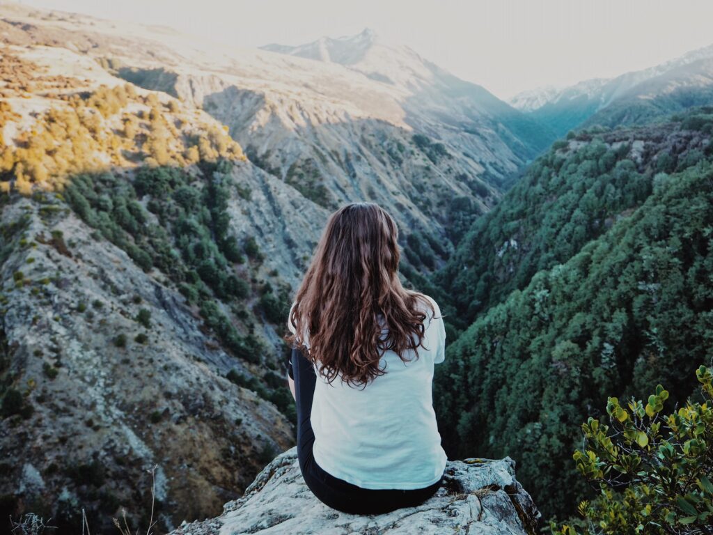 woman sitting on mountain peak