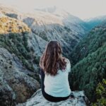 woman sitting on mountain peak