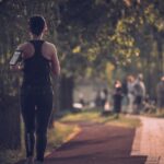 woman in black tank top and black pants walking on sidewalk during daytime